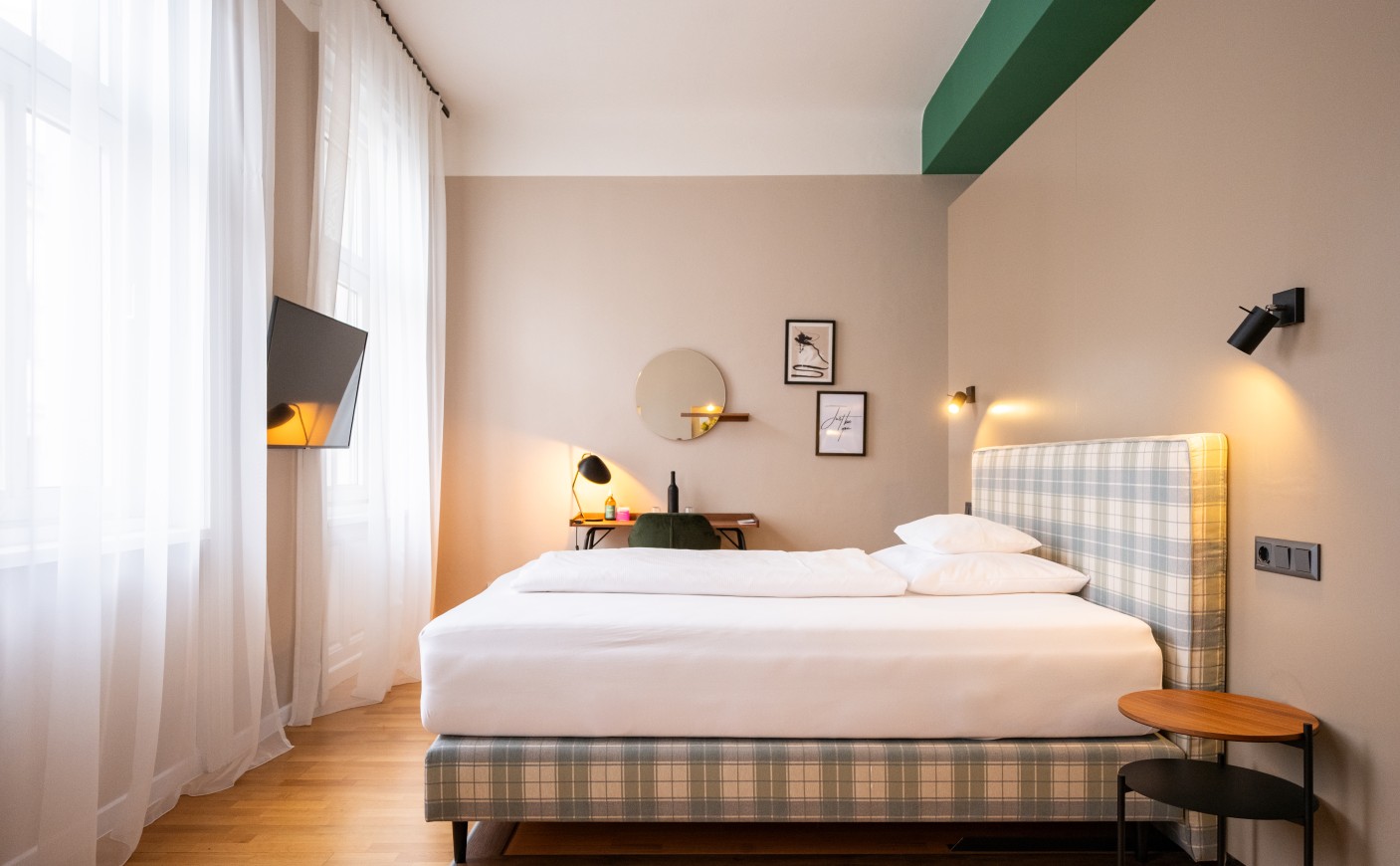 Modern bedroom with plaid bed, wall art, and a mounted TV