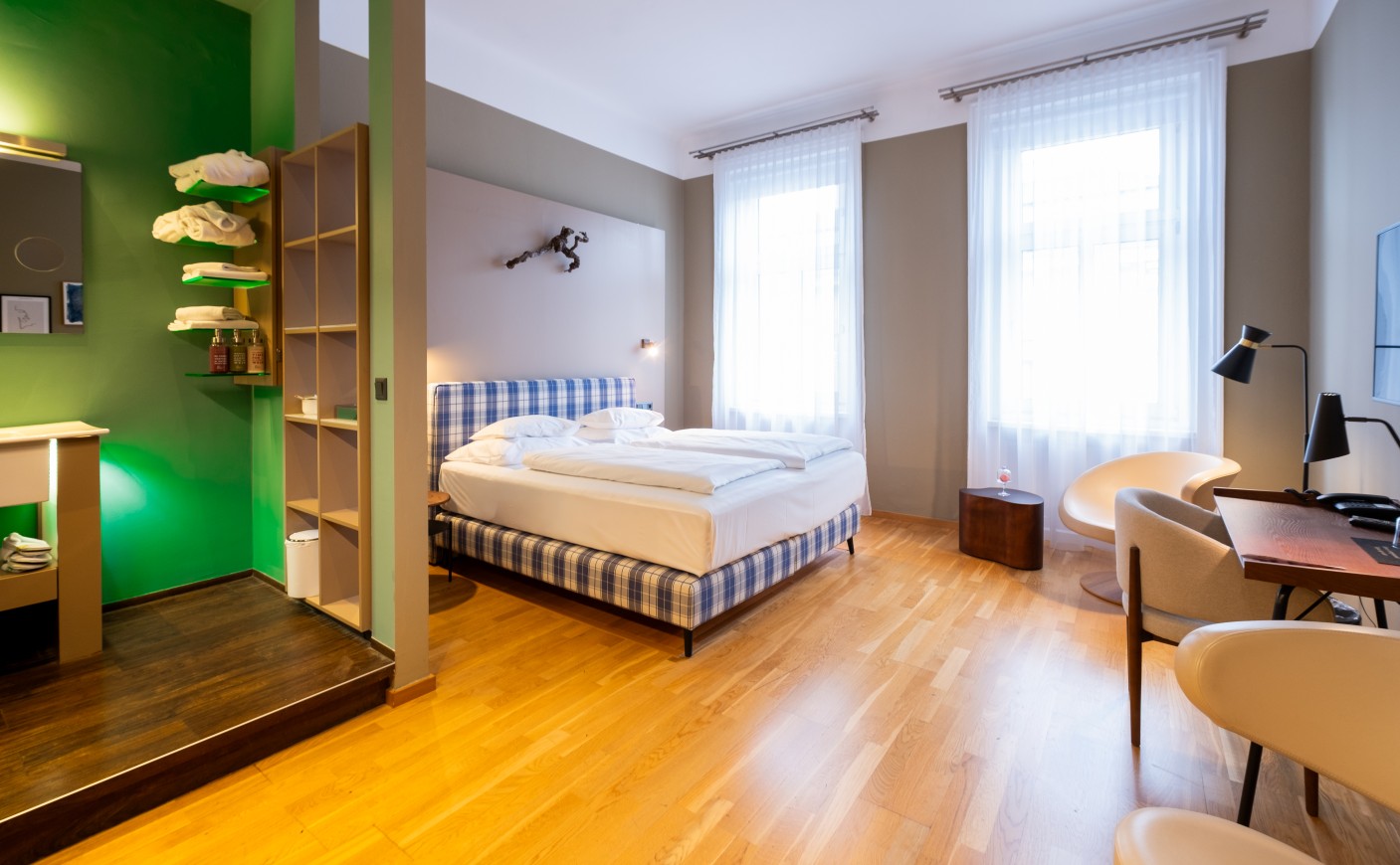 Bright, modern hotel room with a plaid bed and wooden floor
