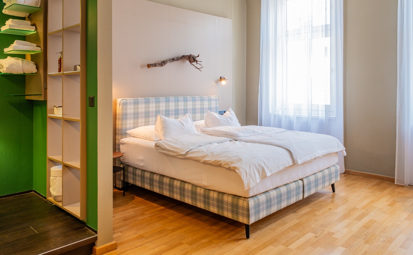 Cozy bedroom with plaid bed, wood floor, and natural light from a large window