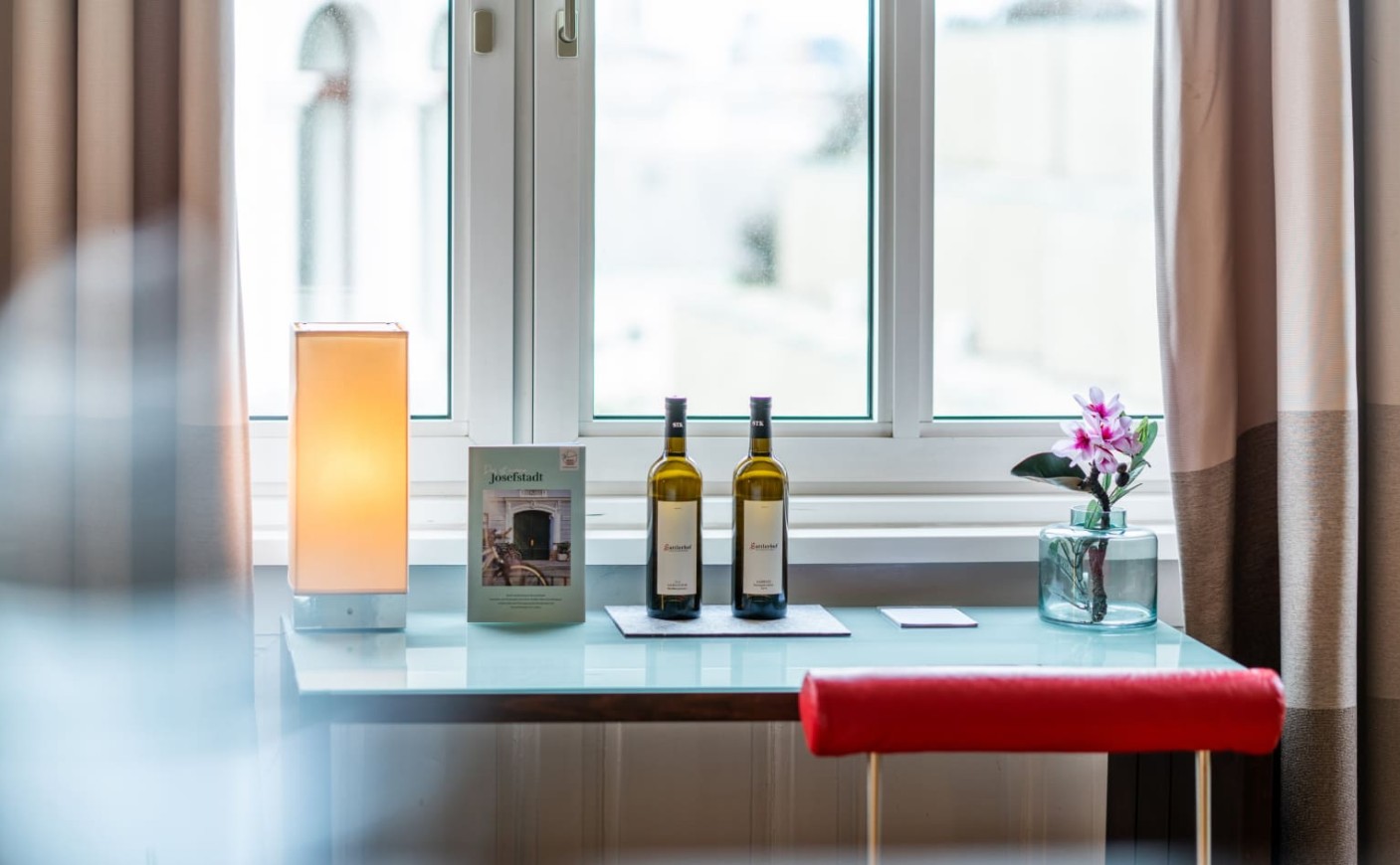 Detailaufnahme von Sitzbank, Wein und Blumen am Fenster im Doppelzimmer Superior